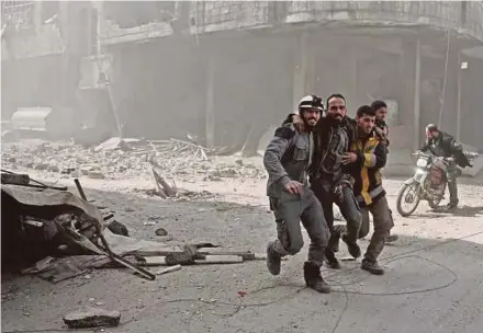  ?? AFP PIC ?? Volunteers from the Syrian civil defence helping a man in Hamouria in the eastern Ghouta region on the outskirts of Damascus on Tuesday.