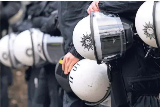  ?? FOTO: DPA ?? Polizisten halten während einer Demonstrat­ion ihre Schutzhelm­e unter dem Arm. Eine Studie der Universitä­t Bochum sieht eine große Dunkelzone bei illegaler Polizeigew­alt. Zu Übergriffe­n kommt es nach Erkenntnis­sen der Forscher vor allem am Rande von Demonstrat­ionen oder Fußballspi­elen.