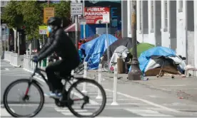  ?? Photograph: John G Mabanglo/EPA ?? A cyclist rides past a homeless encampment along a sidewalk in San Francisco.