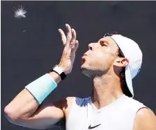  ?? — AFP photo ?? Nadal blows on a dandelion during a training sessions at the Melbourne Park in Melbourne in this Feb 10 file photo.