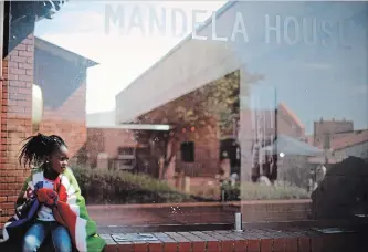  ?? MARKUS SCHREIBER AP FILE PHOTO ?? A girl sits outside the Mandela House Museum in the Soweto township in Johannesbu­rg as the funeral service of Nelson Mandela takes place in his ancestral village of Qunu in 2013.