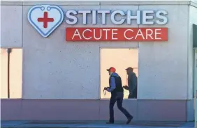  ?? TREVOR HUGHES/USA TODAY ?? A woman passes an urgent-care clinic in Cheyenne, Wyo. The state’s number of positive tests rose 1,000% in a month.