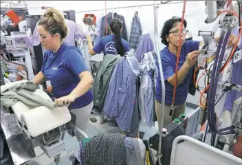  ??  ?? Employees Silvia Casas, left, and Alicia Cabrera utilize a hot press machine at the CD One Price Cleaners on March 21 in Countrysid­e, Ill.