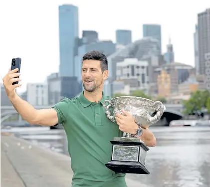  ?? AFP ?? Selfie. Con su celular, Novak Djokovic se toma una foto con el trofeo a orillas del río Yarra, en Melbourne.