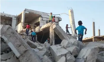  ?? — AFP ?? Syrian children, who fled their homes in Ghouta’s al Marj town, play amidst the debris of buildings in the town of Al Nashabiyah, a rebel stronghold east of the capital Damascus on Tuesday.