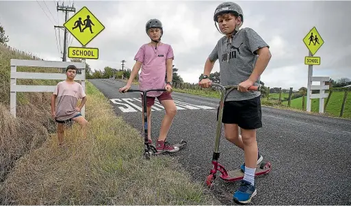  ?? MURRAY WILSON/STUFF ?? From left, Van Campbell, 10, Curtis Mckenzie, 12, and Jacob Matsas, 12, on the road they ride their scooters to school, and the ditch they have to jump into for safety when cars go speeding past.