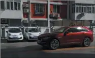  ?? THE ASSOCIATED PRESS ?? An SUV drives past electric cars parked at a charging station outside a residentia­l building in Beijing in April.