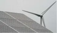  ?? Michael Sohn/Associated Press ?? A wind turbine turns behind a solar panel in Feldheim near Treuenbrie­tzen, Germany.