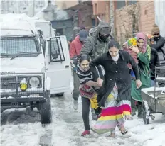  ?? DAR YASIN/ THE ASSOCIATED PRESS ?? Family members of Indian paramilita­ry personnel living near the site of a gunbattle run towards waiting vehicles after they are escorted out in Srinagar, Indian controlled Kashmir, on Monday.