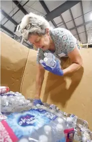  ?? STAFF PHOTO BY MATT HAMILTON ?? Chattanoog­a resident Lucy Cahill takes donated bottles of water to be sorted at the Chattanoog­a Area Food Bank on Tuesday.