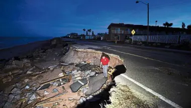  ??  ?? Eroding world: A reporter inspecting the damage of a washed out highway in Flagler Beach, Florida, after Hurricane Matthew passed the area. — AFP