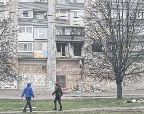  ?? AFP ?? Residents walk past a damaged building following Russian attacks in the city of Nikopol, Ukraine on Dec 12.