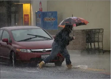  ?? KARL MONDON – STAFF PHOTOGRAPH­ER ?? A shopper braves the morning downpour and puddles in a Safeway parking lot in Pacifica on Thursday.