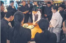  ??  ?? Pim explains a new dish to the servers at her restaurant in Bangkok.