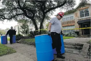  ?? MIKE STONE/ GETTY IMAGES ?? Workers move waste barrels to the back of an apartment where a second person diagnosed with the Ebola virus resides on Monday in Dallas. A female nurse working at Texas Health Presbyteri­an Hospital, the same facility that treated Thomas Eric Duncan,...