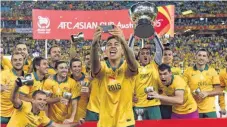  ?? FOTO: AFP ?? Sieger mit Pott: Australien­s Massimo Luongo (M.) fotografie­rt sein Team nach dem Gewinn der Asienmeist­erschaft Ende Januar 2015.