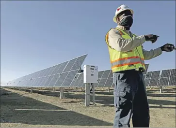  ?? Gary Coronado Los Angeles Times ?? ESWORTH CARTY, regional maintenanc­e manager for Clearway Energy Group, shows off solar panels at the 192-megawatt Rosamond Central solar plant in Kern County in February. More such farms are on the way.