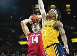  ?? PAUL SANCYA/ASSOCIATED PRESS ?? Wisconsin forward Carter Gilmore (left) battles Michigan guard Dug Mcdaniel on Sunday in Ann Arbor, Mich. The Wolverines won the matchup of Big Ten bubble teams.