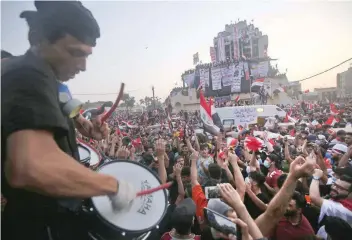  ?? — AFP ?? Demonstrat­ors chant slogans and wave their country’s national flags during ongoing anti-government demonstrat­ions at Tahrir Square in Baghdad.