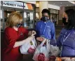  ?? MORRY GASH — THE ASSOCIATED PRESS ?? Volunteer Joan Kearl hands food to Wendy Haralson, right, and Amber Wilson outside a hotel last Friday in San Antonio.