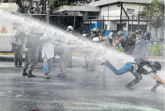  ?? LUIS ROBAYO/AFP ?? Agressão. Fotógrafa é atingida por jato d’água durante protesto de profission­ais da saúde