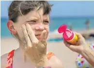  ?? JOE RAEDLE/SUN SENTINEL FILE ?? Top: Mark and Teri Sokol from upstate New York bask in the sun Wednesday next to the pier on Deerfield Beach. The couple said they apply sunscreen to try and protect themselves from the sun, but it doesn’t always work. Above: Sharon Doyle puts sunscreen on the face of 9-year-old Savannah Stidham as they visit the beach in Fort Lauderdale.