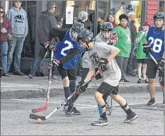  ??  ?? Players took to the street instead of the arena for the JStrong Cup in Yarmouth as spectators watched from the sidewalks, instead of the stands inside a rink.