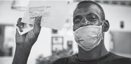  ?? Marie D. De Jesús / Staff photograph­er ?? Clifford Harris proudly holds his COVID-19 vaccinatio­n card after receiving an inoculatio­n at a Harris County Public Health vaccinatio­n site in Dodo's Chicken.