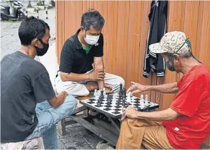  ?? BAY ISMOYO AFP VIA GETTY IMAGES FILE PHOTO ?? Men wearing face masks amid concerns about the coronaviru­s play chess in Jakarta. Old-school games have experience­d a renaissanc­e during the pandemic self-isolation period.