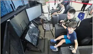  ?? — The Straits Times/Asia News Network ?? Unforgetta­ble time: Visitors experienci­ng manoeuvrin­g an F-16 fighter aircraft using two hand controller­s at the exhibition.