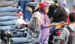  ?? CHUSNUL CAHYADI/JAWA POS ?? BAYAR PARKIR: Pemilik sepeda motor menyerahka­n uang kepada juru parkir di Pasar Baru Kota Gresik.