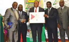  ??  ?? Minister of Industry and Commerce, Dr Mike Bimha (second from right) hands-over the businessma­n of the year award to Destiny of Africa founder, Reverend Obadiah Musindo during last Friday's function