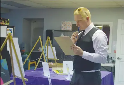  ?? NEWS PHOTO MO CRANKER ?? Karl Holmstrom judges a few pieces of art Friday evening at the Be YOUth Centre’s ‘divercity’ art show. The event was held to get Hat children thinking about diversity in the city.