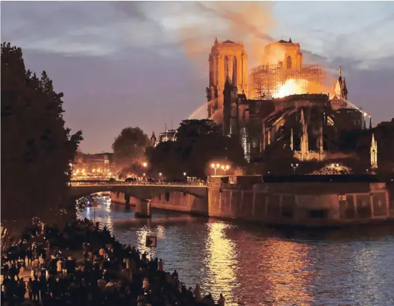  ??  ?? La Catedral de Notre Dame en llamas, vista desde una de las orillas del río Sena, anoche en París.