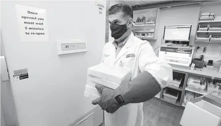  ?? CHRIS O’MEARA/AP ?? Ramon Docobo, assistant director of pharmacy, carries the COVID-19 vaccine Monday at Tampa General Hospital.“I feel like healing is coming,”said a critical care nurse who was inoculated in New York.