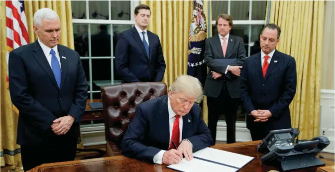  ??  ?? WASHINGTON: In this file photo, President Donald Trump, flanked by Vice President Mike Pence and Chief of Staff Reince Priebus, signs his first executive order on health care in the Oval Office of the White House in Washington.—AP