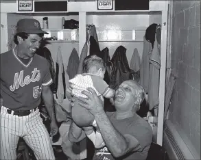  ?? Ray Stubblebin­e / Associated Press ?? Dodgers manager Tom Lasorda lifts up Bobby Valentine, Jr., the four-month-old son of Mets coach Bobby Valentine, left, in the clubhouse at Shea Stadium in 1983.