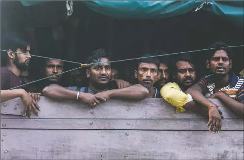  ??  ?? Men from Bangladesh ride in the back of a truck heading to an immigratio­n detention center in Medan, North Sumatra, Indonesia. Officials said a few dozen men were found locked in a house, waiting for a broker to bring them illegally by boat to Malaysia, with some planning to work on palm oil plantation­s.
(AP/Binsar Bakkara)