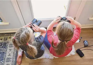  ?? Emily Tubbs/Macaulay Library/Cornell Lab of Ornitholog­y via AP ?? Two girls watch birds through a window with binoculars in Elm Grove, La., during the Great Backyard Bird Count in February 2022. About 385,000 people from 192 countries took part in the 2022 count, and their results have been used by scientists to study bird population­s worldwide.