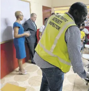  ?? ?? An inspector from the Island Traffic Authority (right), Minister of Education Fayval Williams (left) and Minister of Transport and Mining Audley Shaw (second left) observe as students assemble for the written ITA road code test.