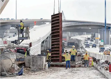  ?? Will Thorne photos ?? Workers remove a form from a new sign post during constructi­on on Highway 290. Constructi­on to widen the northwest freeway from Loop 610 to Waller County began in 2011. Officials say finishing touches will be complete by the time Houstonian­s ring in...