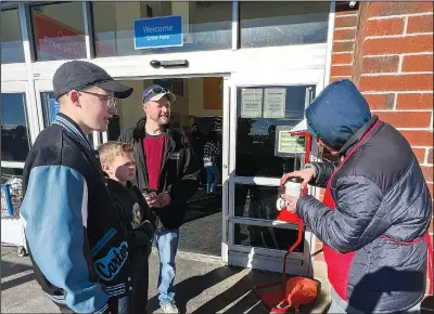  ?? (AP/The Wyoming Tribune Eagle/Rhianna Gelhart) ?? Adam Van Der Hoeven and his two sons, Carter Van Der Hoeven and Cyler Van Der Hoeven, hand Salvation Army volunteer James Weber a hot coffee Dec. 21 at the Cheyenne Police Department in Cheyenne, Wyo. Carter, Cyler and their dad, Adam, worked to do 25 acts of kindness during the month of December in honor of their late mother and wife who passed away last year.