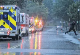  ?? Elizabeth Conley / Houston Chronicle ?? An EMT jumps over a puddle as ambulances line up to evacuate some of the ICU patients out of Ben Taub Hospital as Hurricane Harvey inched its way through the area last week.