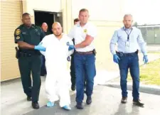  ?? KIMBERLY C. MOORE/THE LEDGER VIA AP ?? Quadruple murder suspect Bryan Riley is led from the Polk County Sheriff’s Office in Lakeland, Fla., on Sunday by Deputy Steve Neil, left, Captain Bart Davis and Detective Brett Bulman.