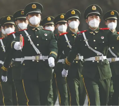  ?? CARLOS GARCIA RAWLINS / REUTERS ?? Paramilita­ry officers march while wearing face masks to contain the spread of COVID-19 in Beijing on Wednesday.
