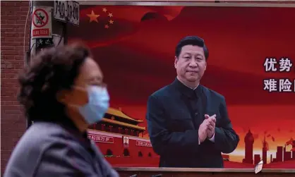  ??  ?? A woman wearing a protective mask in front of a portrait of President Xi Jinping, Shanghai. Photograph: Aly Song/Reuters