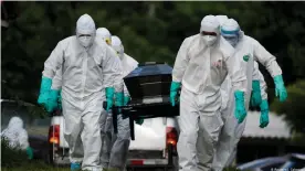  ??  ?? Cemetery workers carry the coffin of a man who died of the disease caused by the new coronaviru­s (COVID-19)