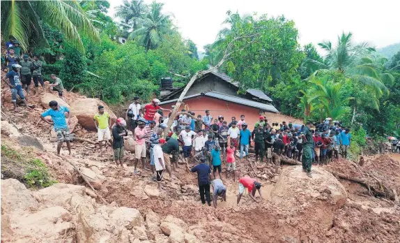  ?? AP ?? Sri Lankans watch military rescue efforts after a landslide in Bellana village.