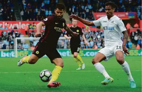  ?? Reuters ?? Manchester City’s Sergio Aguero (left) tries to weave his way past Swansea City’s Kyle Naughton during the Premier League clash at Liberty Stadium yesterday. Aguero fired Manchester City into a ninth-minute lead and also had a hand in Raheem Sterling’s...