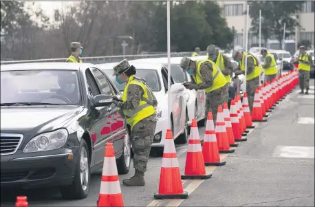  ?? JAE C. HONG — THE ASSOCIATED PRESS ?? Members of the National Guard help motorists check in at a federally-run COVID-19vaccinat­ion site set up on the campus of California State University of Los Angeles in Los Angeles, Feb. 16.